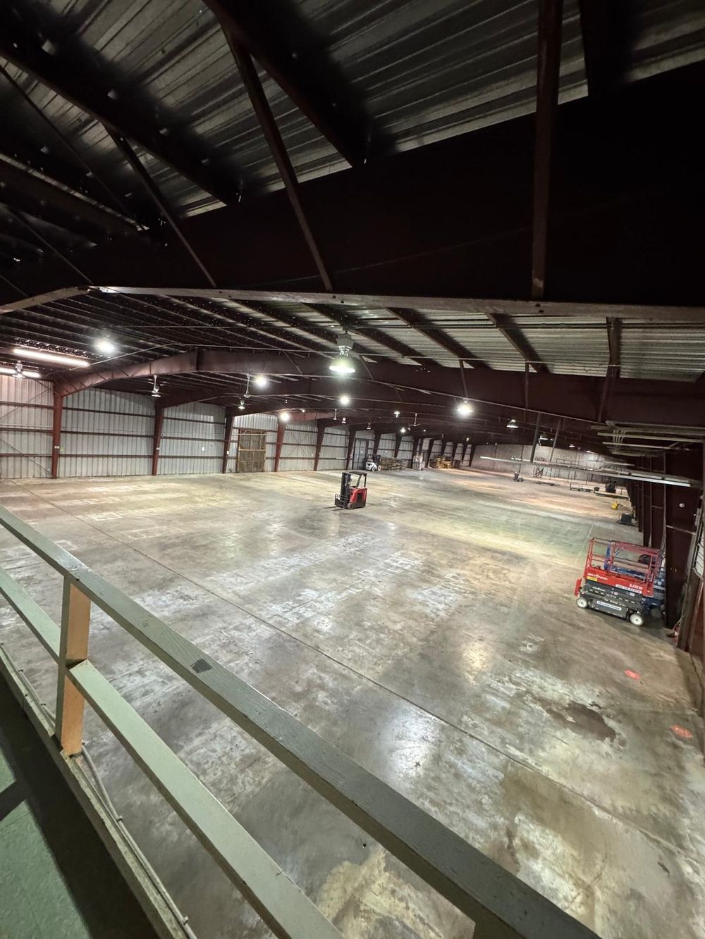 After: the same warehouse floor seen from the mezzanine, cleared and empty