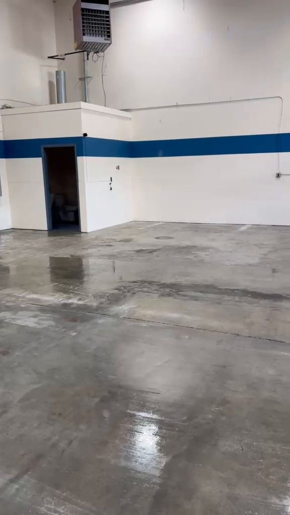 After: the blue-striped warehouse room emptied with the floor washed