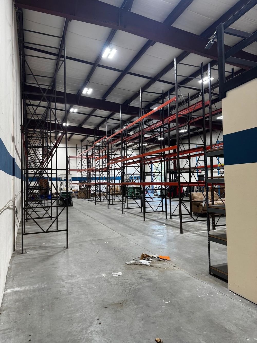 Before: black and orange pallet racking along the blue-striped wall