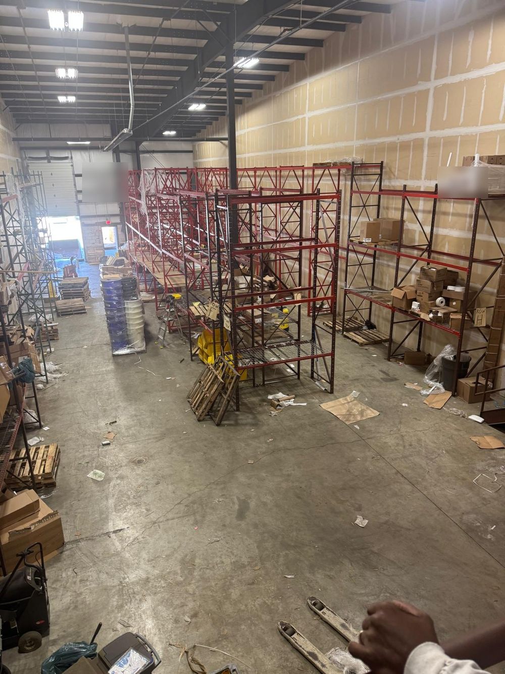 Before: red pallet racking with debris and pallets across the floor